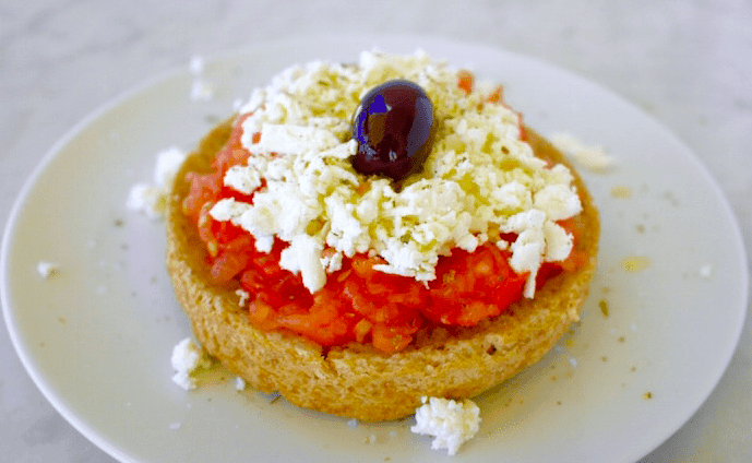 -Dakos salad, made of hard bread (paximadi or rusks, lightly soaked in water so that they are softened), accompanied with tomato pieces, mizithra cheese and olive oil.