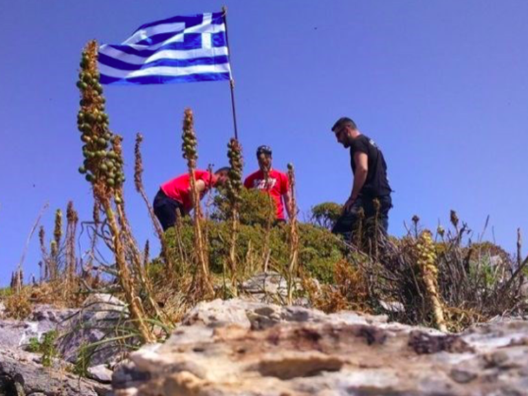 Three mates raise Greek flag on highest point of rocky island for Turkey to see