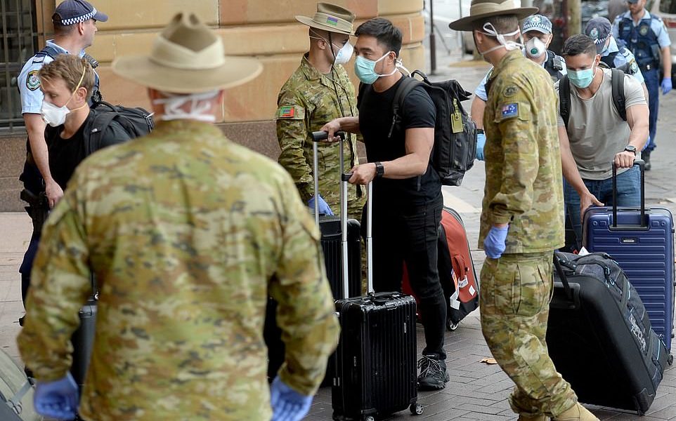 Returning overseas travellers are ushered into Sydney's InterContinental Hotel by the Australian Police and Defence Forces to begin their compulsory 14-day quarantine