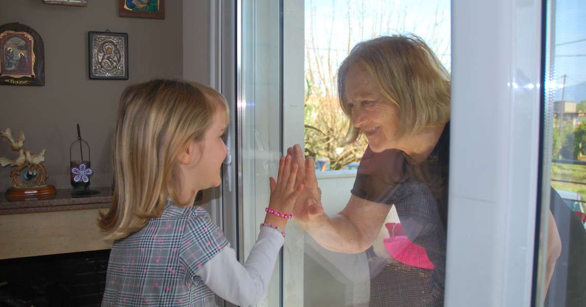 Greek grandparent greeting her grandchild through glass in the covid_19 pandemic