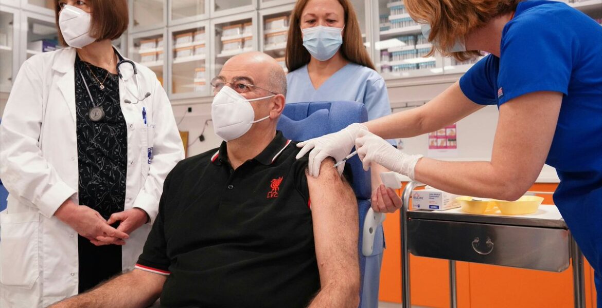Greek FM Dendias gets COVID vaccine in a Liverpool T-shirt