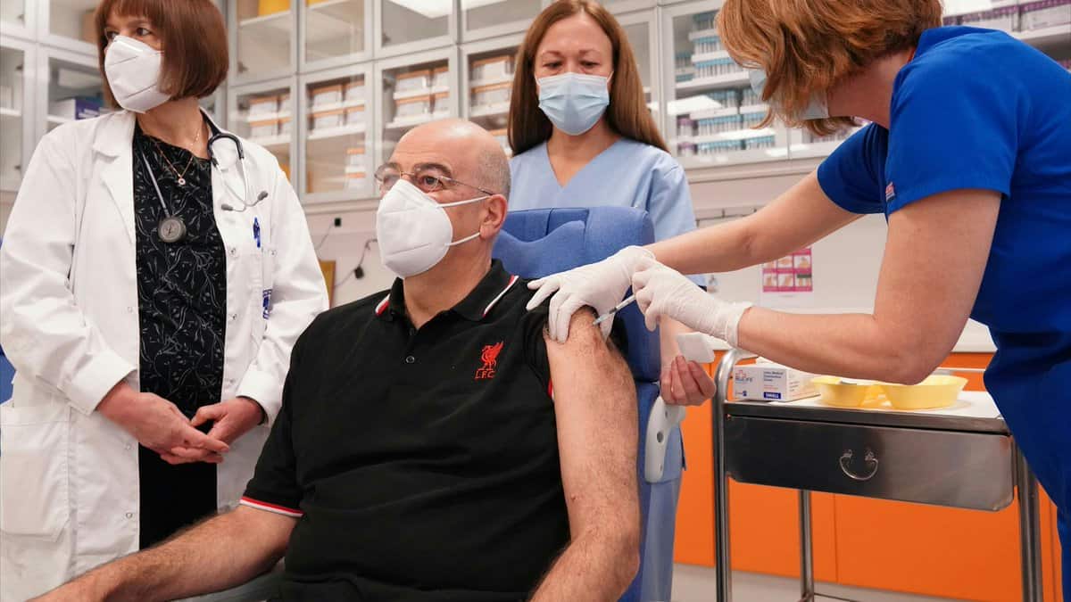 Greek FM Dendias gets COVID vaccine in a Liverpool T-shirt