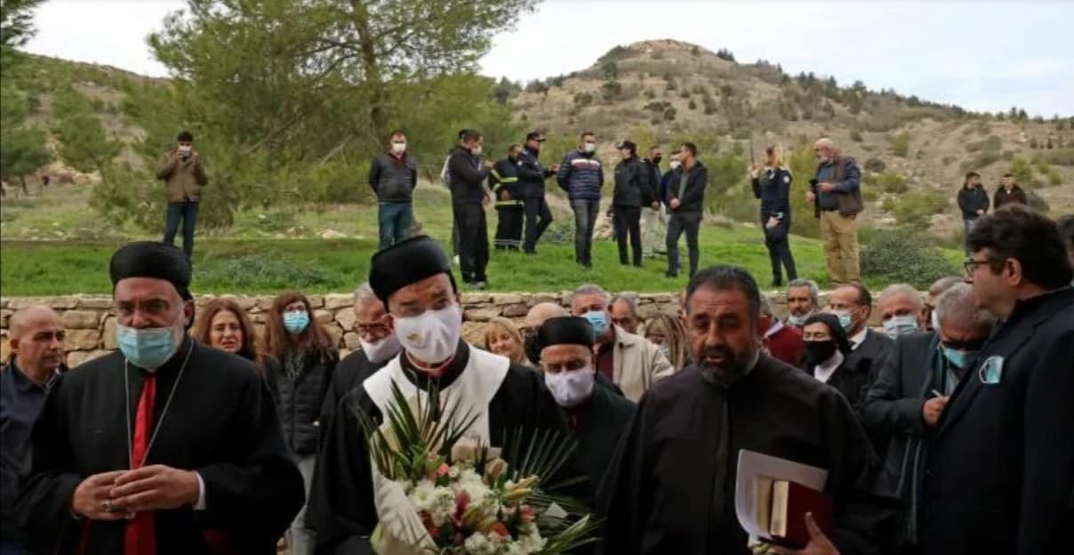Turkish security forces (back) keep watch as Lebanon's Maronite Patriarch Bechara al-Rahi (C, with flowers) arrives at the small Agia Marina Maronite church in occupied Northern Cyprus (AFP/Christina ASSI)
