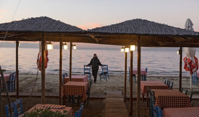 A waiter collects chairs from the beach at an empty seaside restaurant in Thessaloniki, Greece. Greek unemployment