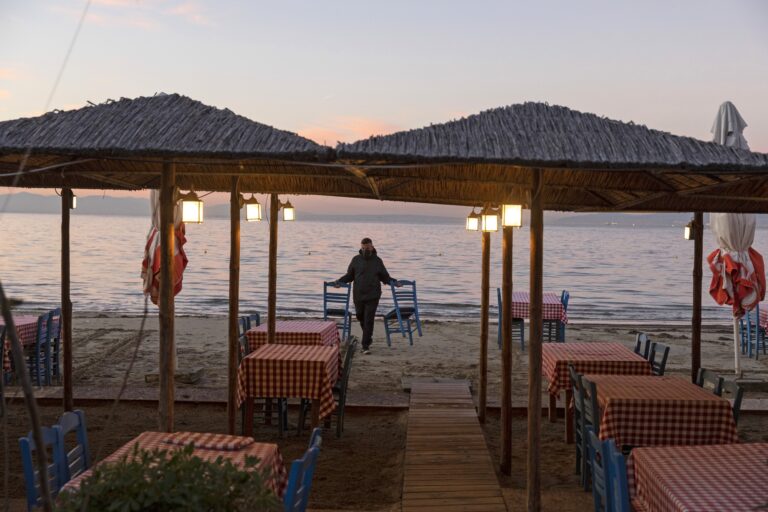 A waiter collects chairs from the beach at an empty seaside restaurant in Thessaloniki, Greece. Greek unemployment