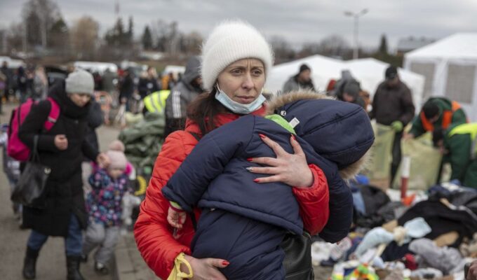 Ukraine Greece A woman carries her child as she arrives at the Medyka border crossing after fleeing from the Ukraine, in Poland, Monday. [AP]
