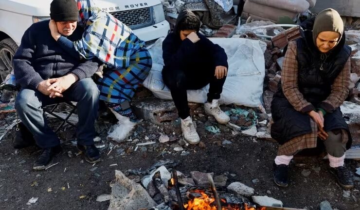 People sit next to a fire near the site of a collapsed building following an earthquake in Kahramanmaras, Turkey on Feb. 7, 2023. (Suhaib Salem/Reuters) Cyprus