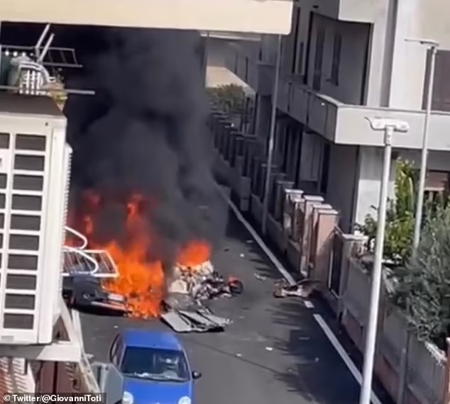 One of the two aircraft fell onto a street below onto a parked car infront of what appeared to be a residential building from footage of the aftermath (pictured). Onlookers heard him screaming for help before the plane's engine exploded, killing him
