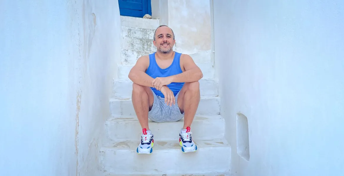 Tony Kariotis, founder of Greece Media, sitting on stairs in Greece.