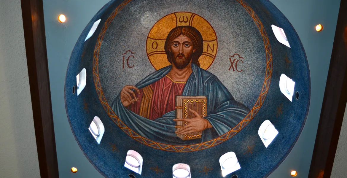 This is an image of Christ as Pantocrator in the Byzantine mosaic style, characteristic of Eastern Orthodox Religious art iconography. The IC and the XC are abbreviations for the Greek word meaning “Jesus Christ”. In his left hand, Jesus holds the New Testament and the gesture of his right hand indicates a blessing.