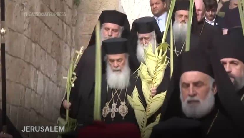 Orthodox Christians walk holding palm branches on the eve of Palm Sunday holiday on the Mount of Olives in Jerusalem, Saturday