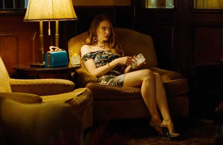 emma stone sitting in a chair in a dimly lit room in the kinds of kindness trailer