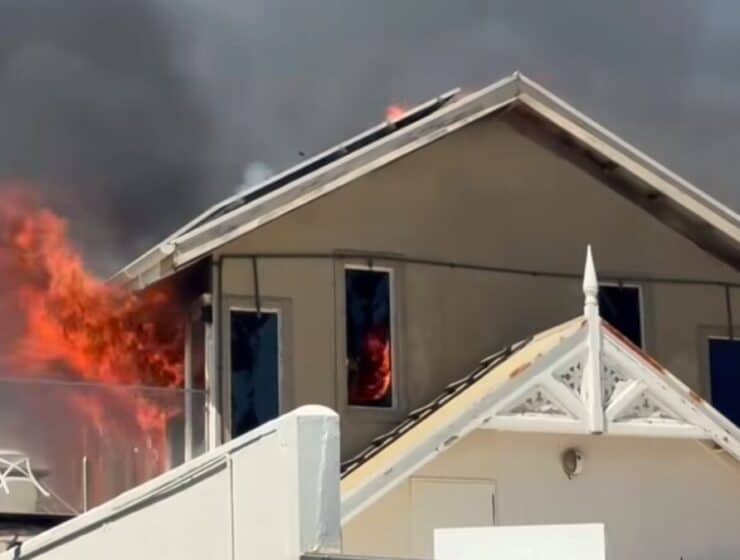 Fire rescue operation as house catches fire with flames and smoke emergency response in progress.