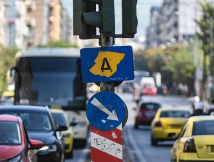 Traffic signs on busy city street in Greece, urban traffic control, Greek road signs, city transportation, urban mobility infrastructure, Greek city traffic management, cityscape with vehicles and signage, Greek urban transport system, street scene Greece, road safety in Greek cities.